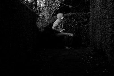 Side view of man sitting on seat in forest
