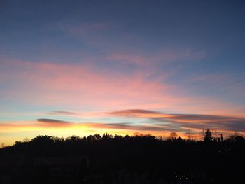 Silhouette trees against dramatic sky during sunset