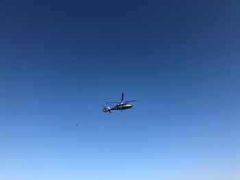 Low angle view of helicopter flying against clear blue sky