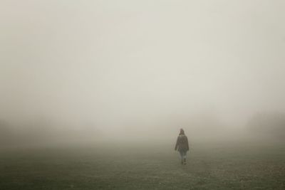 Person walking on field in foggy weather