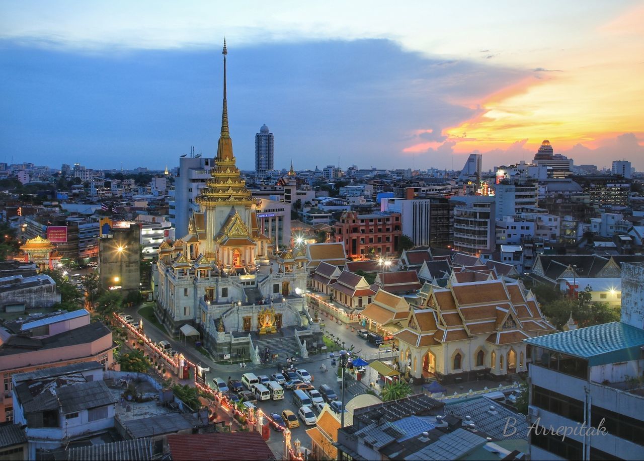 HIGH ANGLE VIEW OF ILLUMINATED CITY AGAINST SKY DURING SUNSET