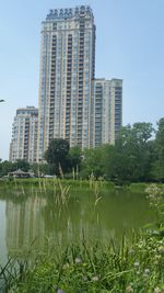 Reflection of buildings in lake against clear sky