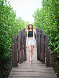 Portrait of young woman standing against trees