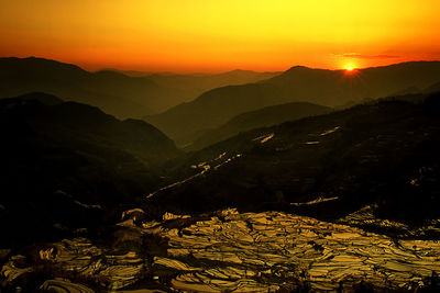 Scenic view of mountains against orange sky