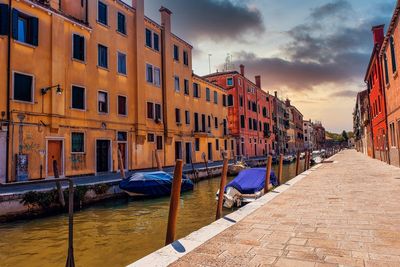 Canal amidst buildings against sky during sunset