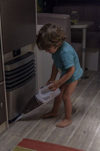 A sweet little boy vacuums the caravan while on vacation. a cute boy is cleaning the caravan.