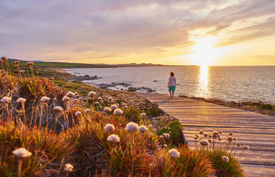 Italy, sardinia, lu litarroni, senior woman on wooden boardwalk at sunset