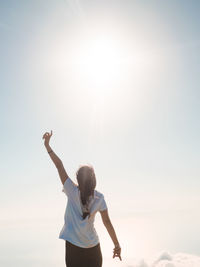 Rear view of woman standing against sky on sunny day