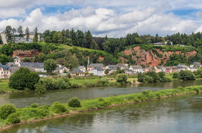 Scenic view of river by buildings against sky