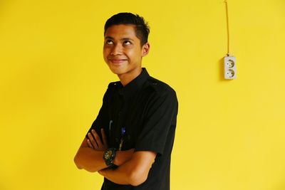 Smiling young man against yellow wall