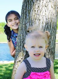 Portrait of smiling siblings by tree at park