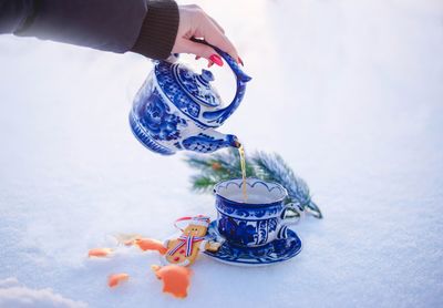 Cropped hand of woman holding container on table