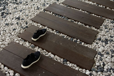 High angle view of old shoes on boardwalk amidst pebbles