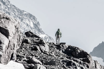 Low angle view of man standing on cliff against sky