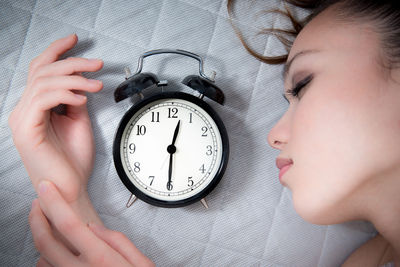 Close-up of woman sleeping by alarm clock on bed