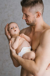 Father with a beard holds a newborn in his arms on a grey background. holiday concept 