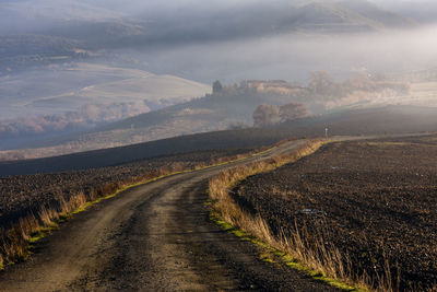 Road amidst field against sky