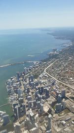 High angle view of cityscape by sea against clear sky
