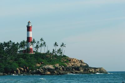 Lighthouse by sea against clear sky