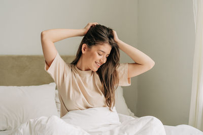 Side view of young woman looking away while lying on bed at home