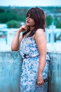 Young woman looking away while sitting outdoors