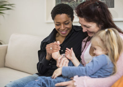 Happy lesbian couple with girl in living room