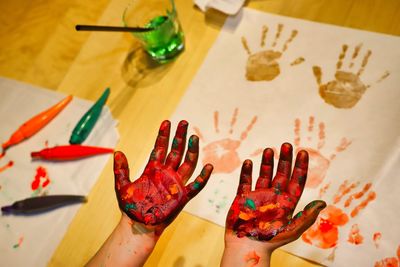 High angle view of messy hands over painting on table