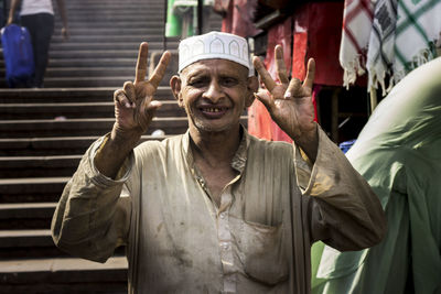 Portrait of man in traditional clothing gesturing against steps