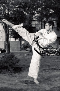 Full length of young man doing karate on field