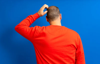 Rear view of man standing against blue background