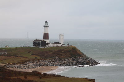 Lighthouse by sea against sky