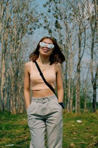 Young woman wearing sunglasses standing in forest