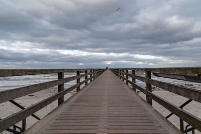 Wooden pier leading towards sea against sky