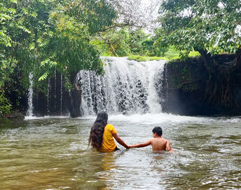 Rear view of man surfing in waterfall