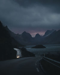 Scenic view of sea and mountains against sky at dusk