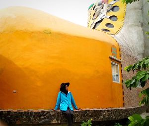 Woman sit in front of the yellow wall