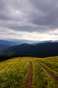 Scenic view of fields against cloudy sky