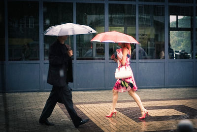 Woman with umbrella standing on wet street