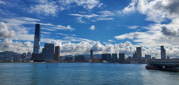 Sea by modern buildings against sky in city