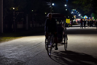 Full length of man cycling bicycle cart on road at night