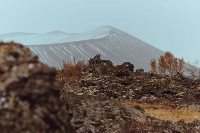 Crater of a volcano with lava fields in the foreground