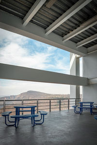 Brutalist concrete architecture, large space overlooking a ravine, blue dining benches. beam 