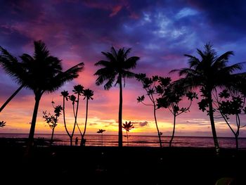 Silhouette palm trees on beach against sky during sunset