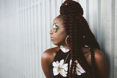 Young woman with braided hair standing by metal wall