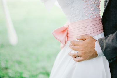Midsection of groom hold bride hips with ring on finger