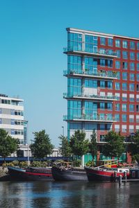 Canal amidst buildings against clear blue sky