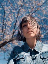 Low angle portrait of young woman with tousled hair in park during spring