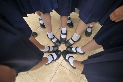 Low section of schoolgirls on tiled floor in classroom