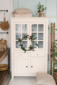 White wardrobe with a christmas wreath, skis and decor in the living room of the house