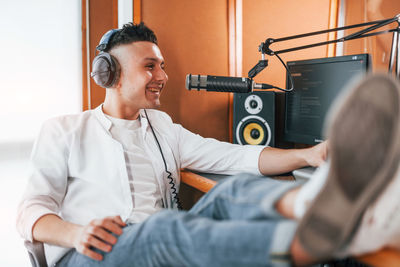 Talks and uses mic. young man is indoors in the radio studio is busy by broadcast.